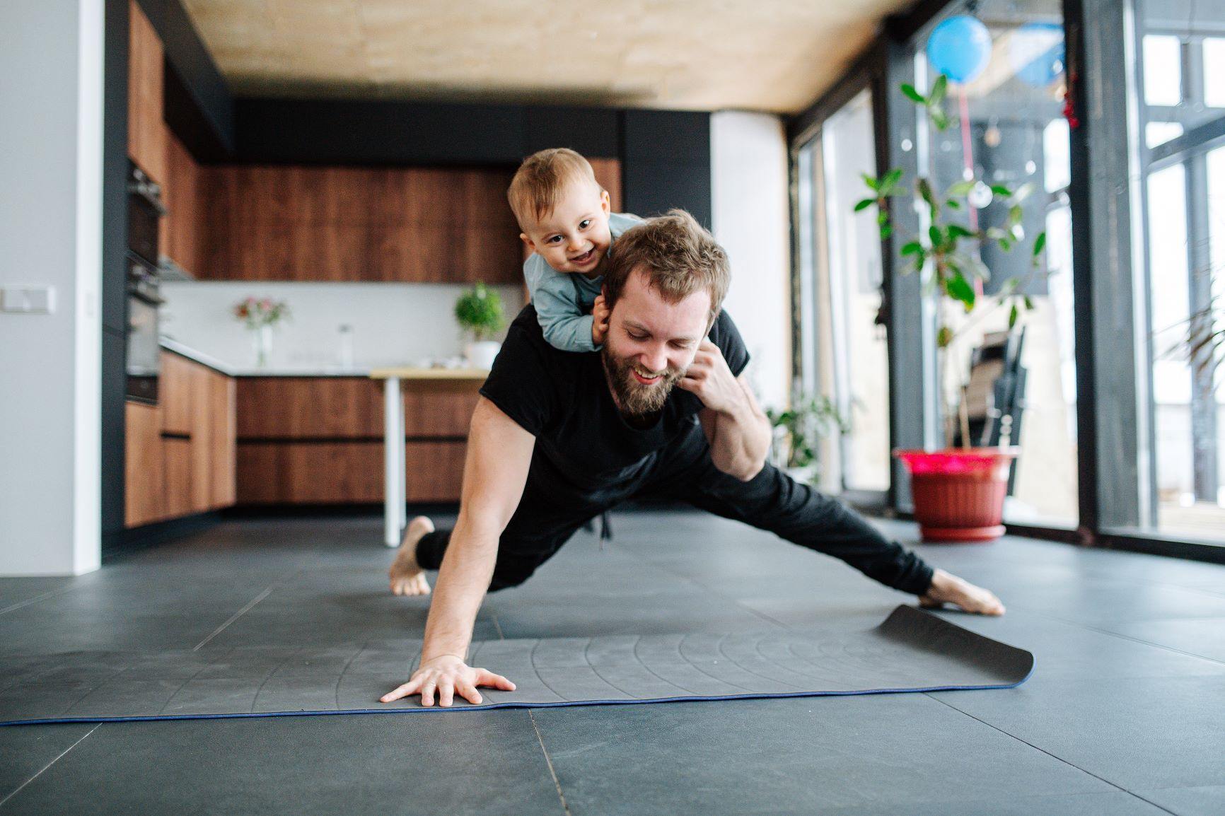 Man doing one arm push up with small child on his back