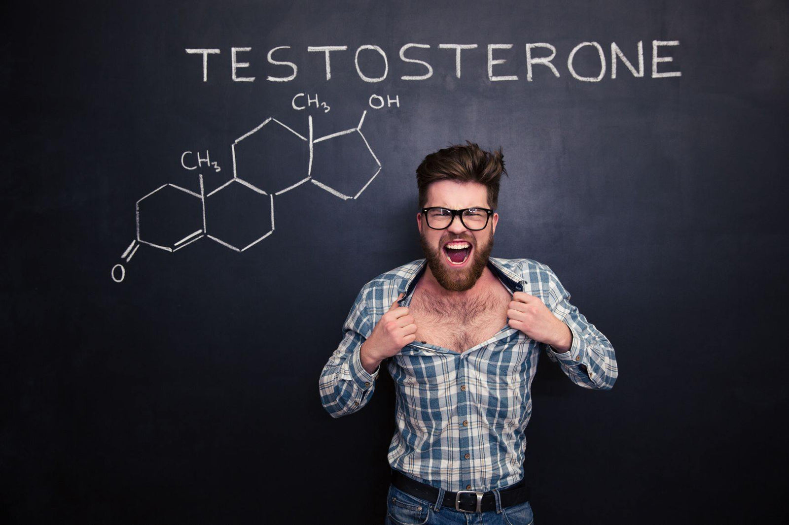 male ripping his shirt open in front of blackboard with testosterone written out as well as the chemical formula for testostrone