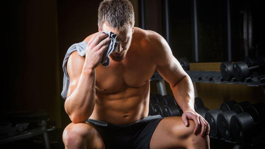 fit man sitting in a gym holding a 